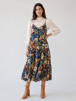 A Western model with dark‑brown hair, solid‑color background #efefef, stylish outfit, no plain white T‑shirt or jeans. The camisole loose‑fit dress features a large floral pattern.
