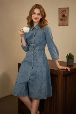 Create a product model image of a denim dress. The model should be a young, beautiful, playful, and sweet Caucasian woman. The background can be any everyday setting. The model should be holding a coffee cup in one hand and resting the other hand on a walnut-colored table, with one leg casually crossed over the other. She should be leaning casually against the table or wall. The overall lighting should be somewhat dim, creating a retro yet sweet atmosphere with a film poster-like quality.